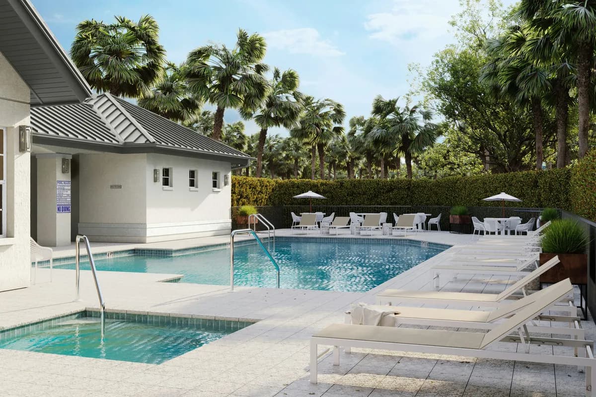 A community clubhouse pool and spa with white lounge chairs, shaded patio tables, and palm trees under a blue sky