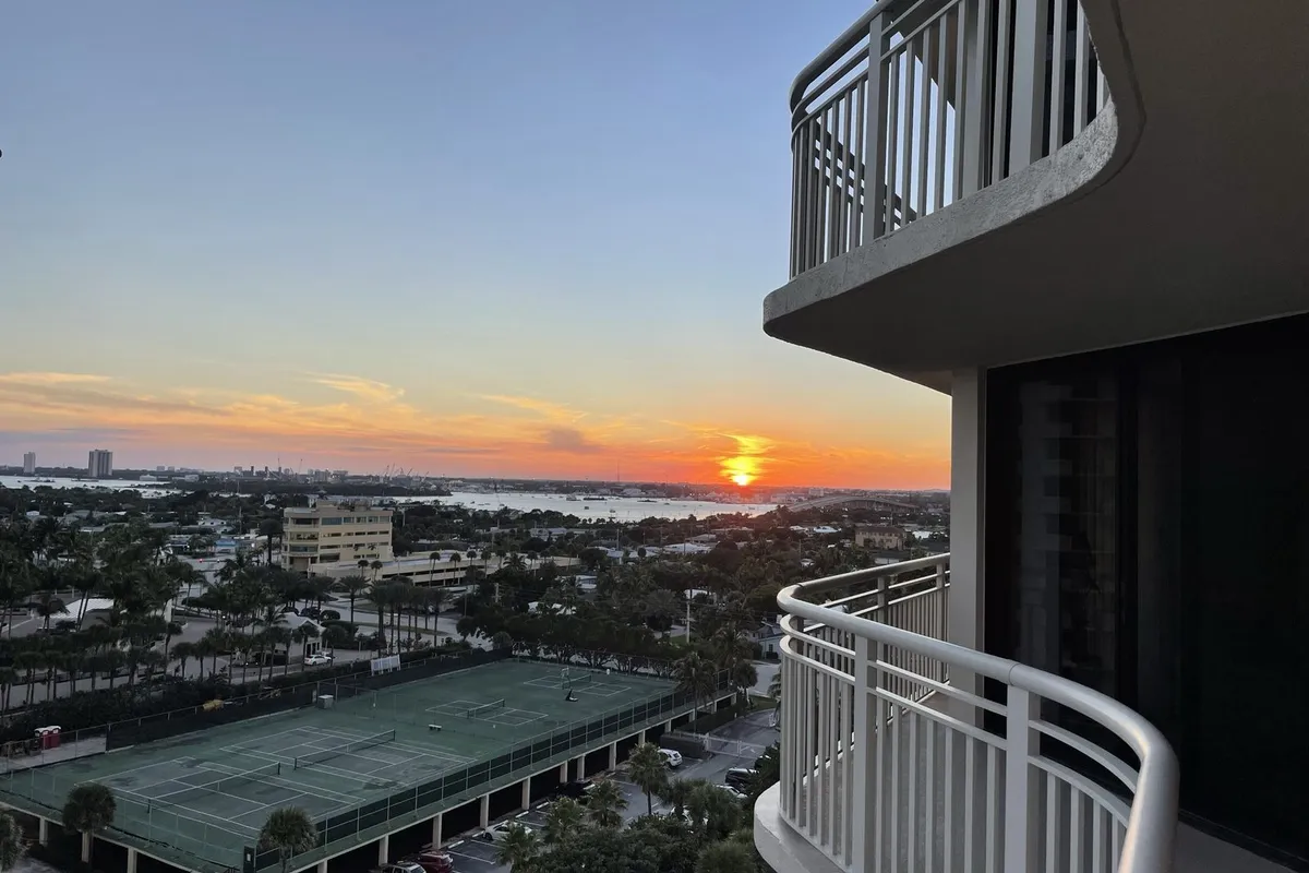 Sunset over the Intracoastal seen from a high balcony at Tiara on Singer Island, with tennis courts, palms and buildings below