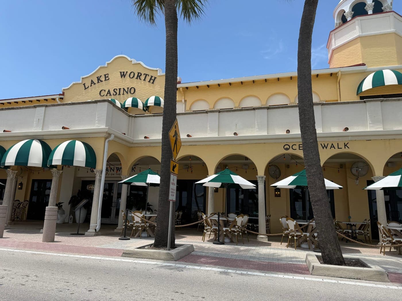 The Lake Worth Casino Building arcade seen straight on, with café tables under the arches and green-and-white awnings