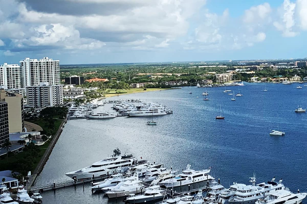 A high-rise beside a marina and a wide waterway, seen from above