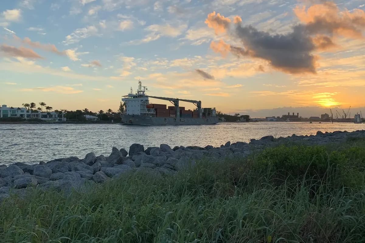 A container ship passing through the Lake Worth Inlet at sunset, seen from the south tip of Singer Island