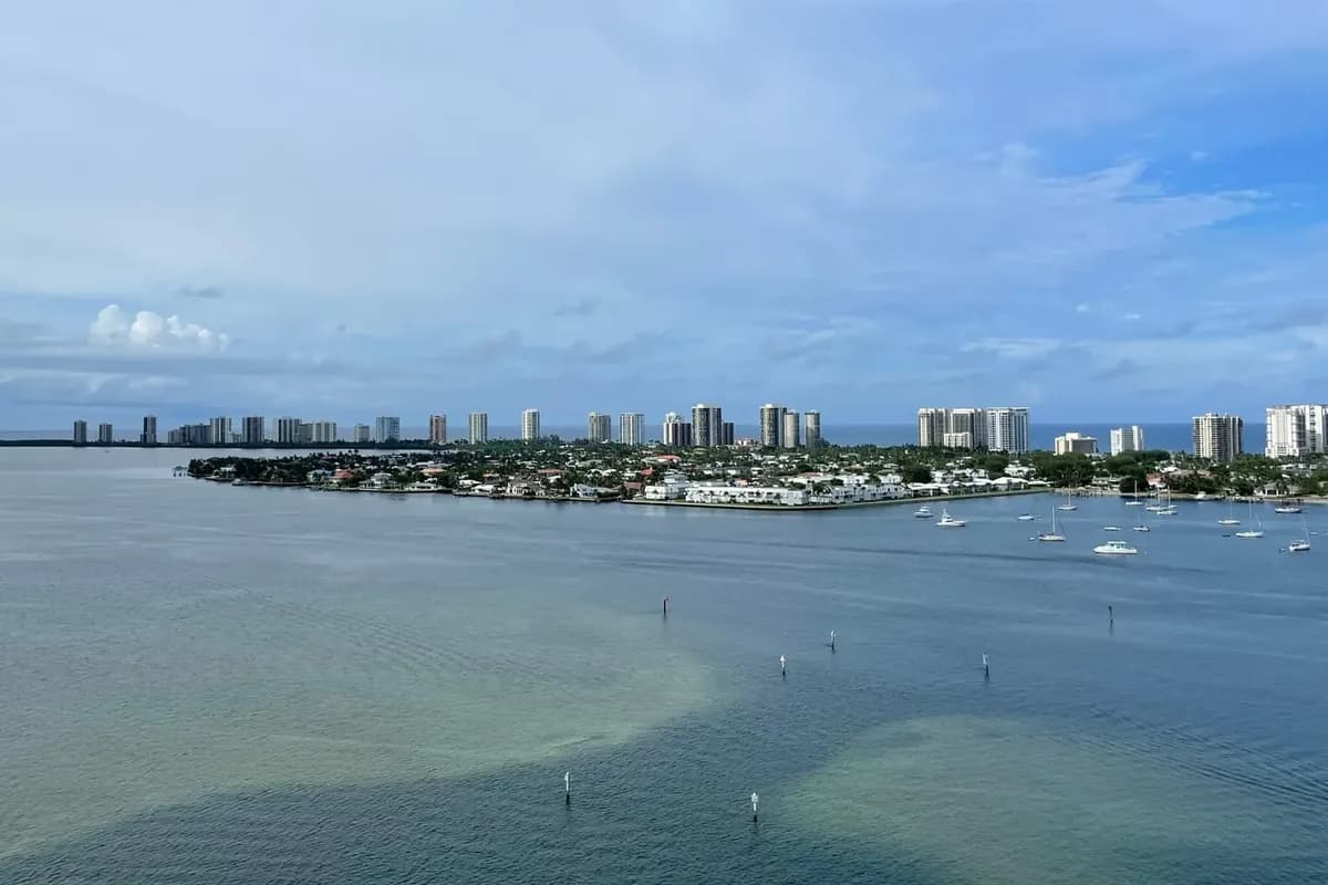 Singer Island's high-rises and a point of waterfront homes seen across the Lake Worth Lagoon, with boats at anchor