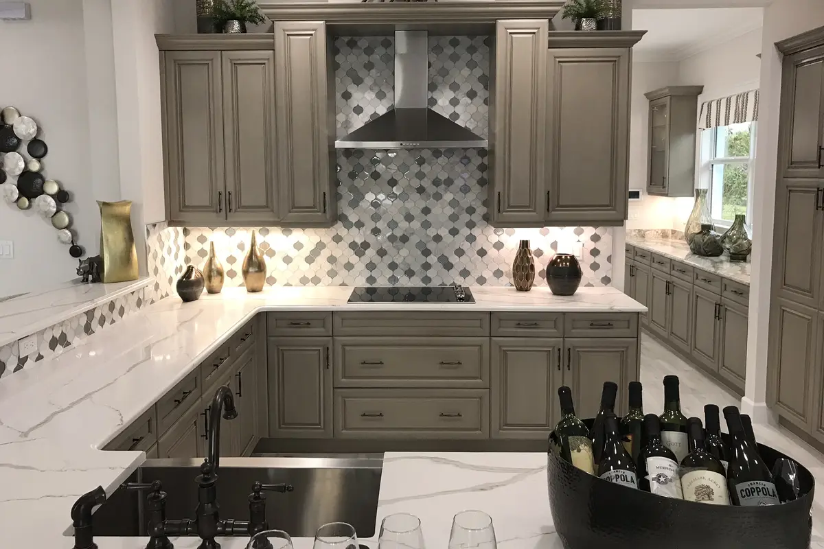 A staged kitchen in a Minto model home in Westlake with gray raised-panel cabinets, a patterned tile backsplash and marble-look counters