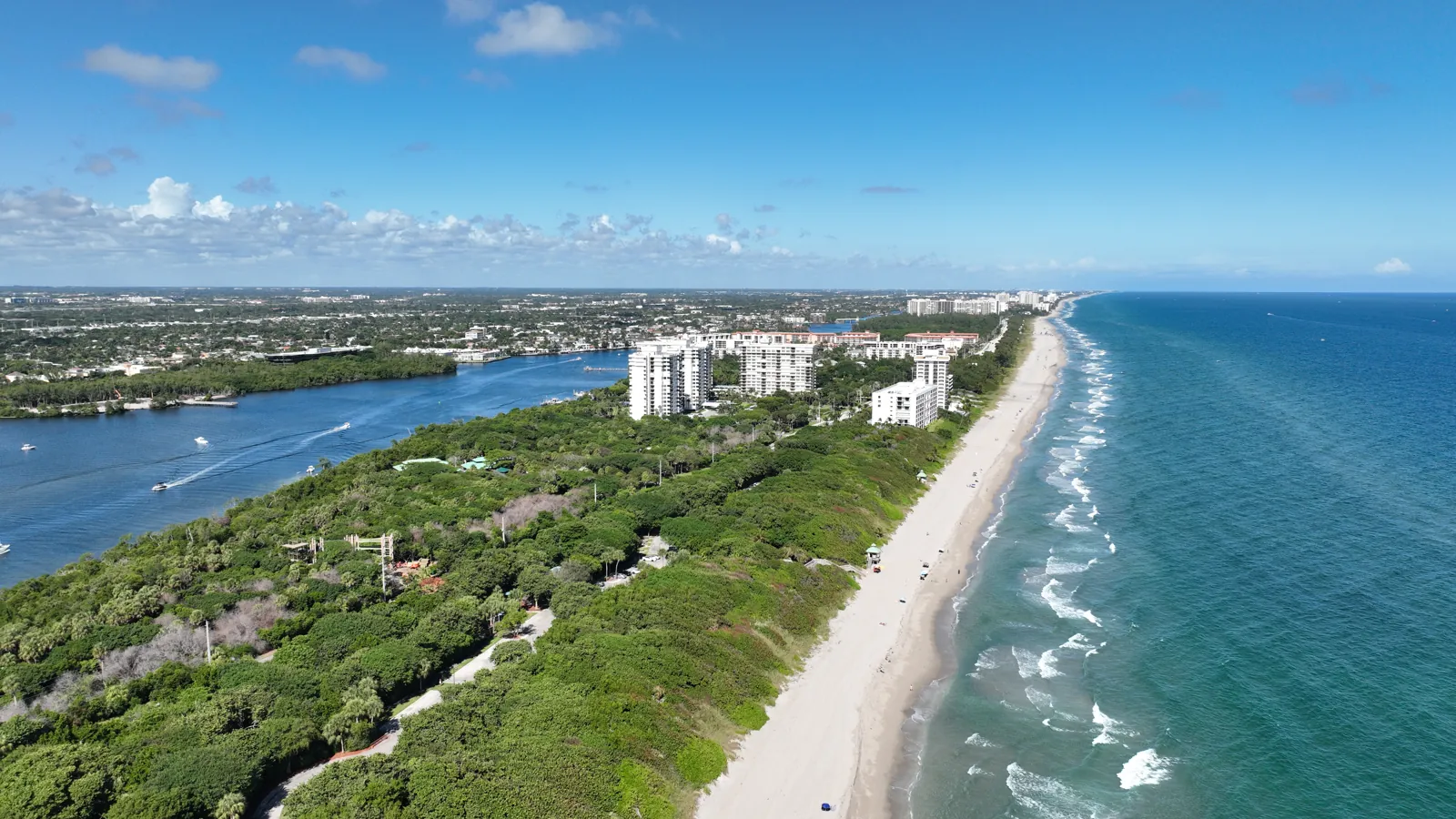 Aerial of barrier-island coastline with Intracoastal Waterway, coastal hammock, sandy beach and high-rise condo towers