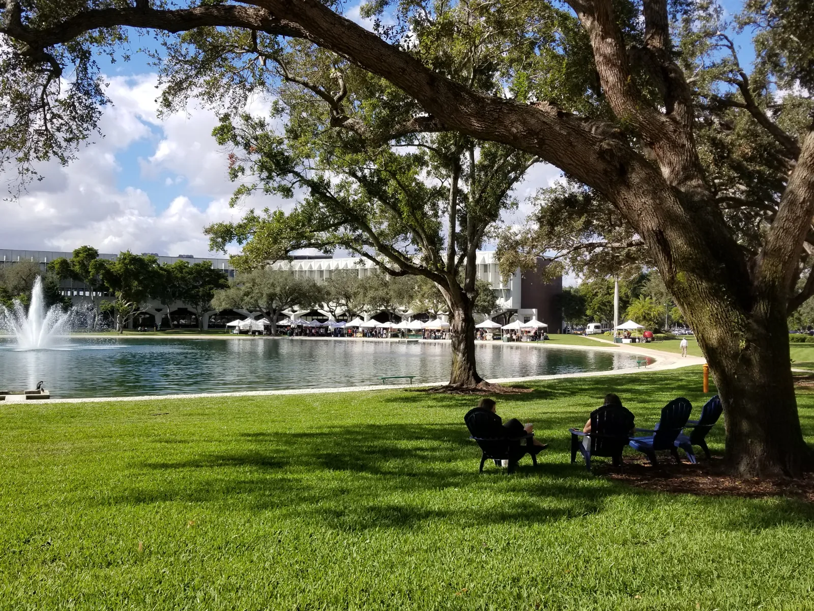 Lakeside lawn with live oaks, fountain, and outdoor market tents