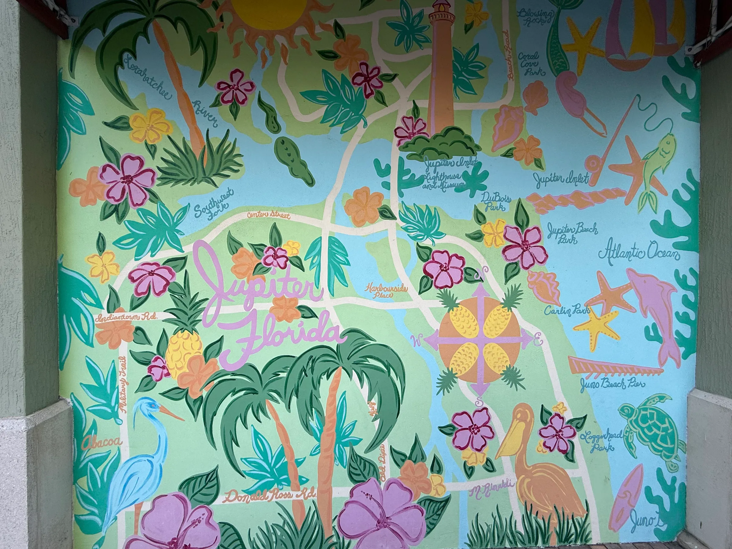 A hand-painted mural map of Jupiter showing the Loxahatchee River, the lighthouse, the inlet, the beaches and Harbourside Place