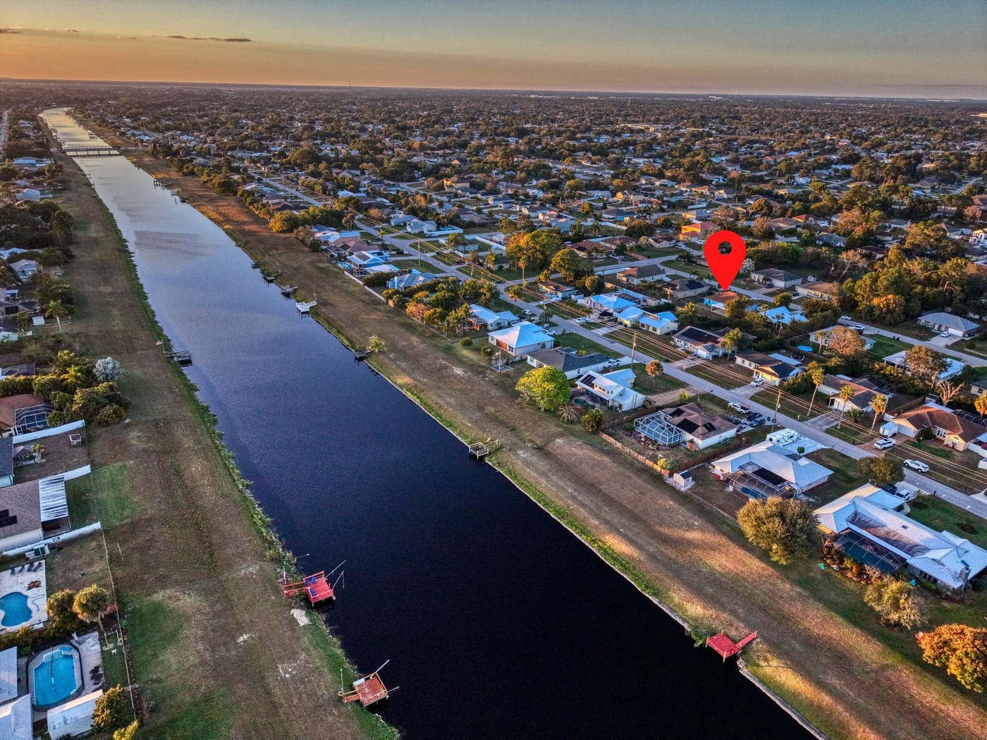 Aerial view over rows of single-family homes along a straight canal in Port St. Lucie at sunset