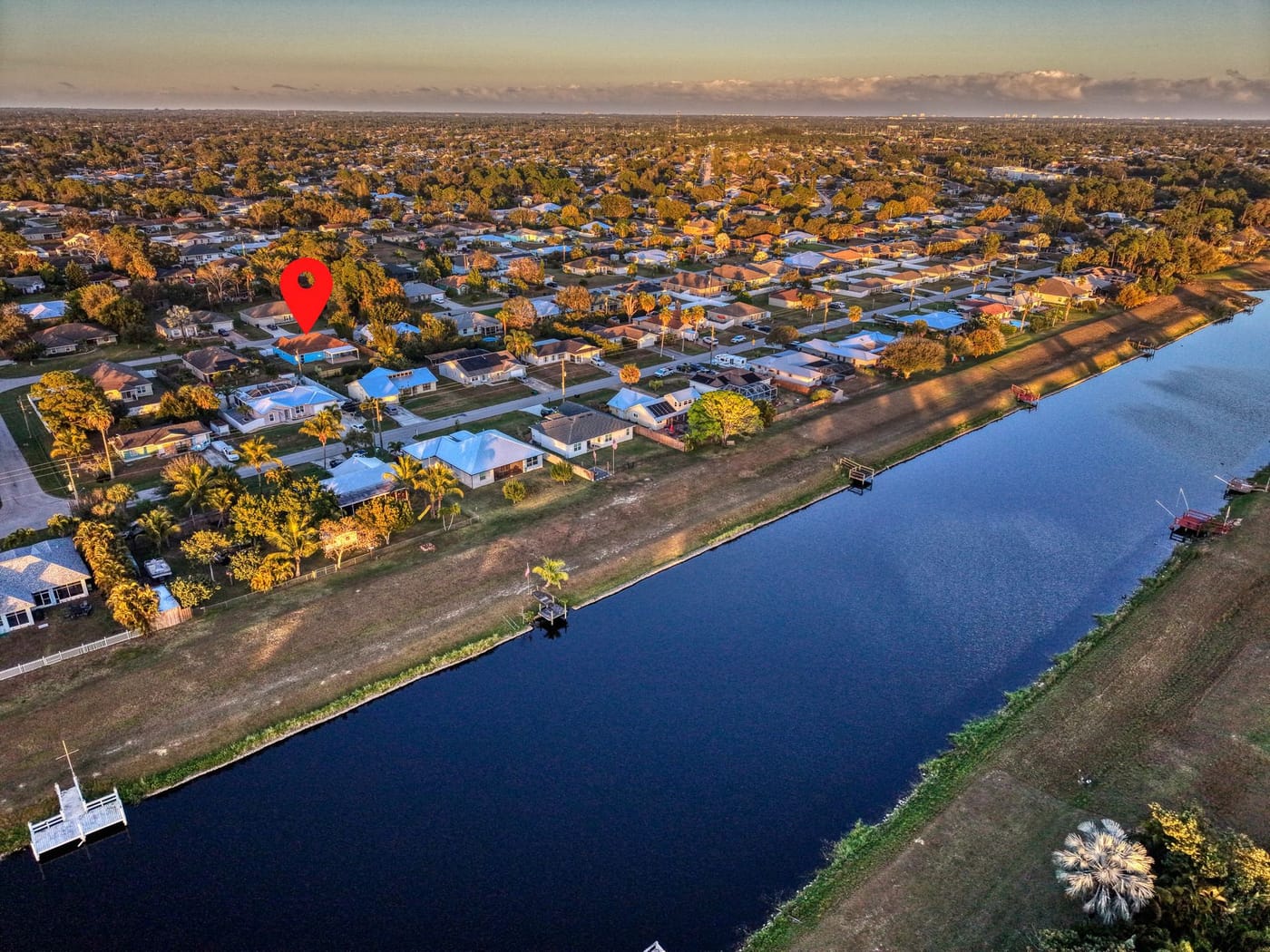 Aerial view over Port St. Lucie homes and streets beside a wide canal at sunset