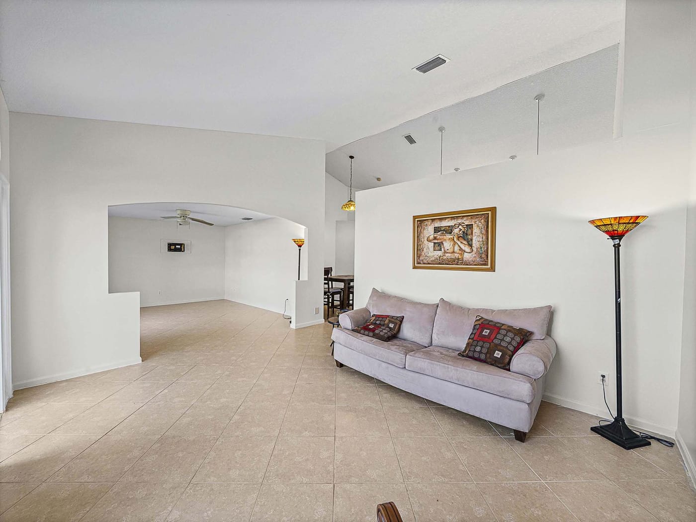 A bright living area with vaulted ceilings, arched windows and tile floors