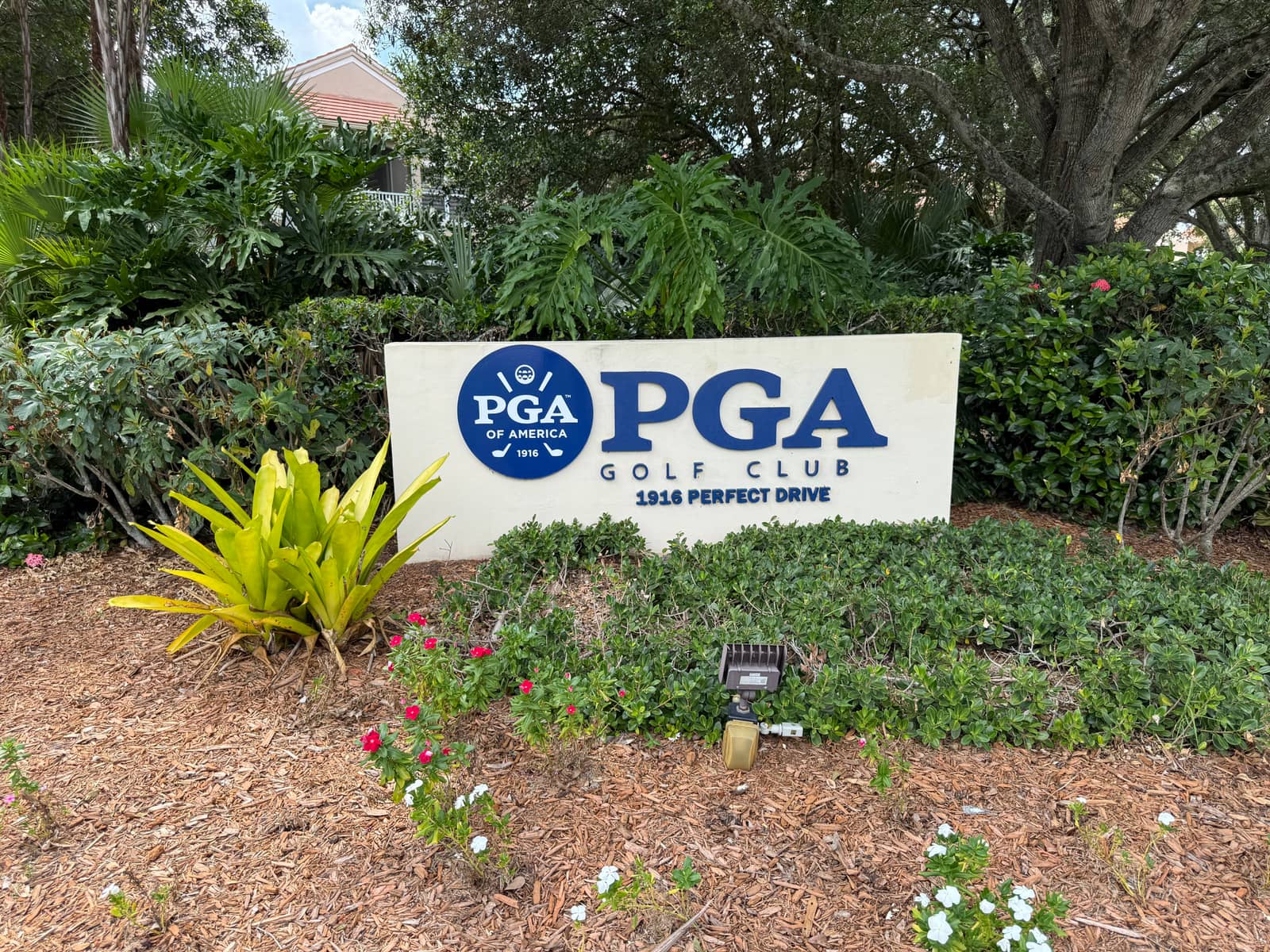 The PGA Golf Club monument sign at 1916 Perfect Drive, surrounded by tropical planting