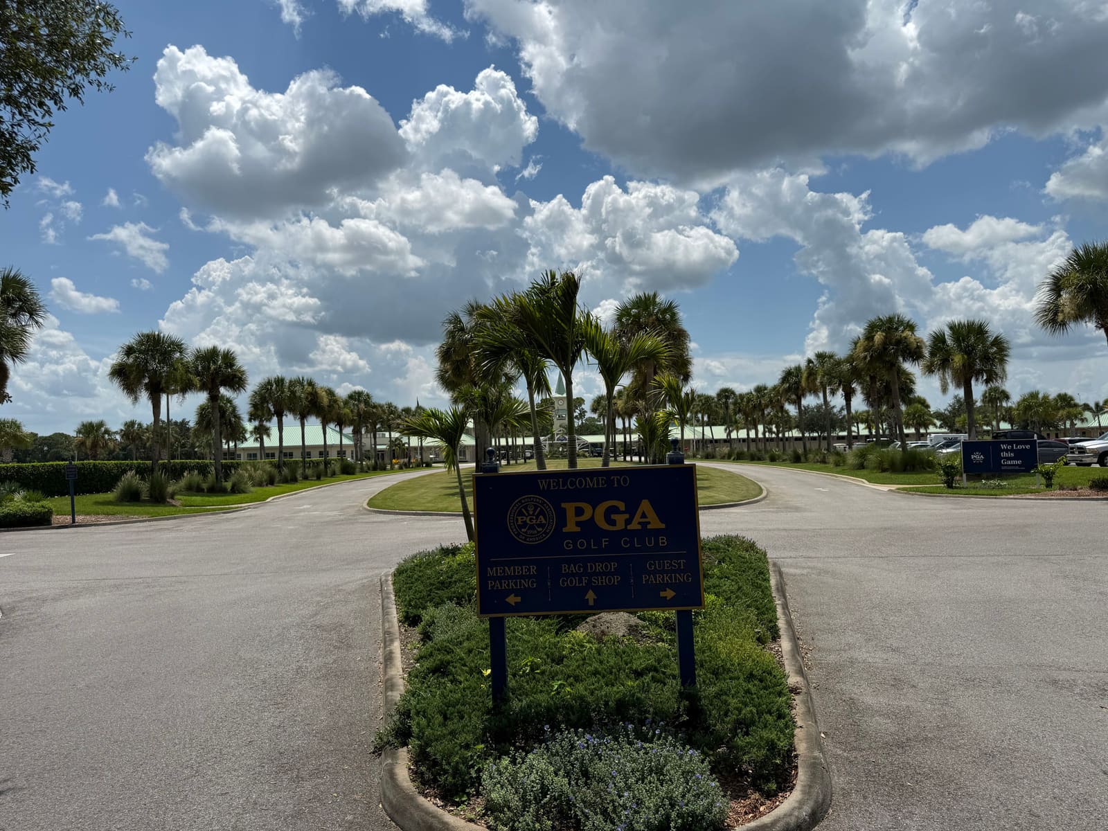 The PGA Golf Club entrance sign on its palm-ringed roundabout, directing traffic to member parking, bag drop and guest parking