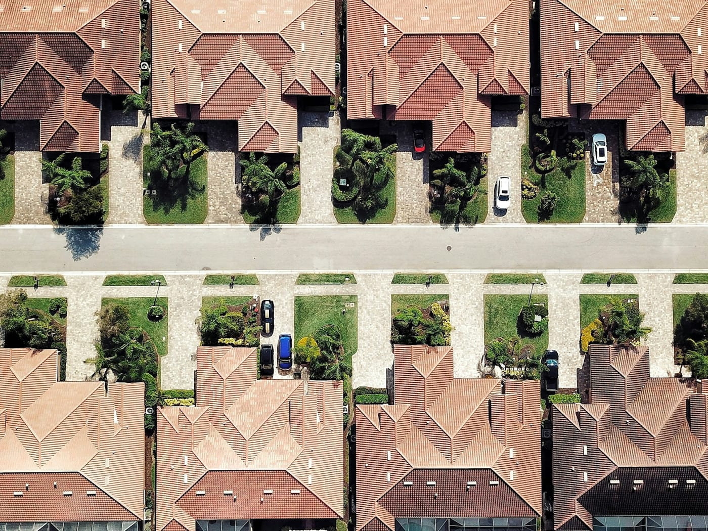 Aerial view looking straight down on rows of tile-roofed houses either side of a residential street