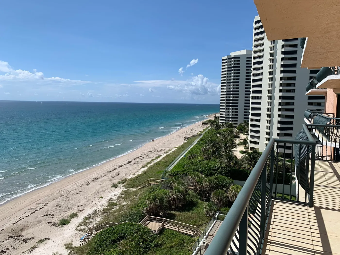 A view north along the beach from a condominium balcony, with dune walkovers crossing the vegetation and towers along the shore