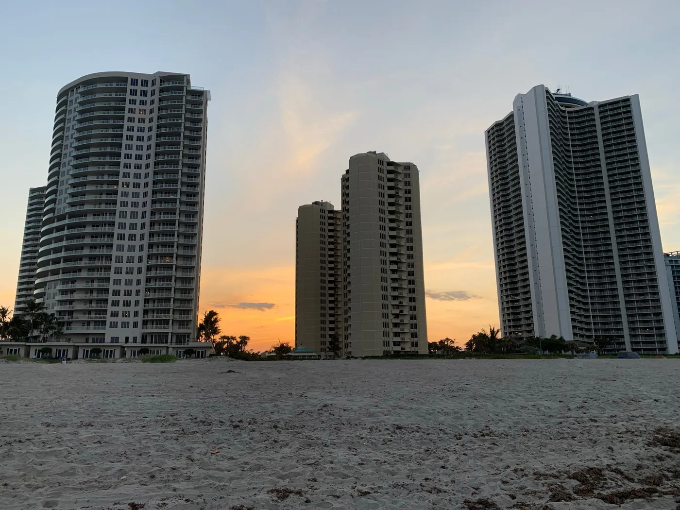 Four towers seen from the beach at sunset, with a pavilion roof in the gap between them