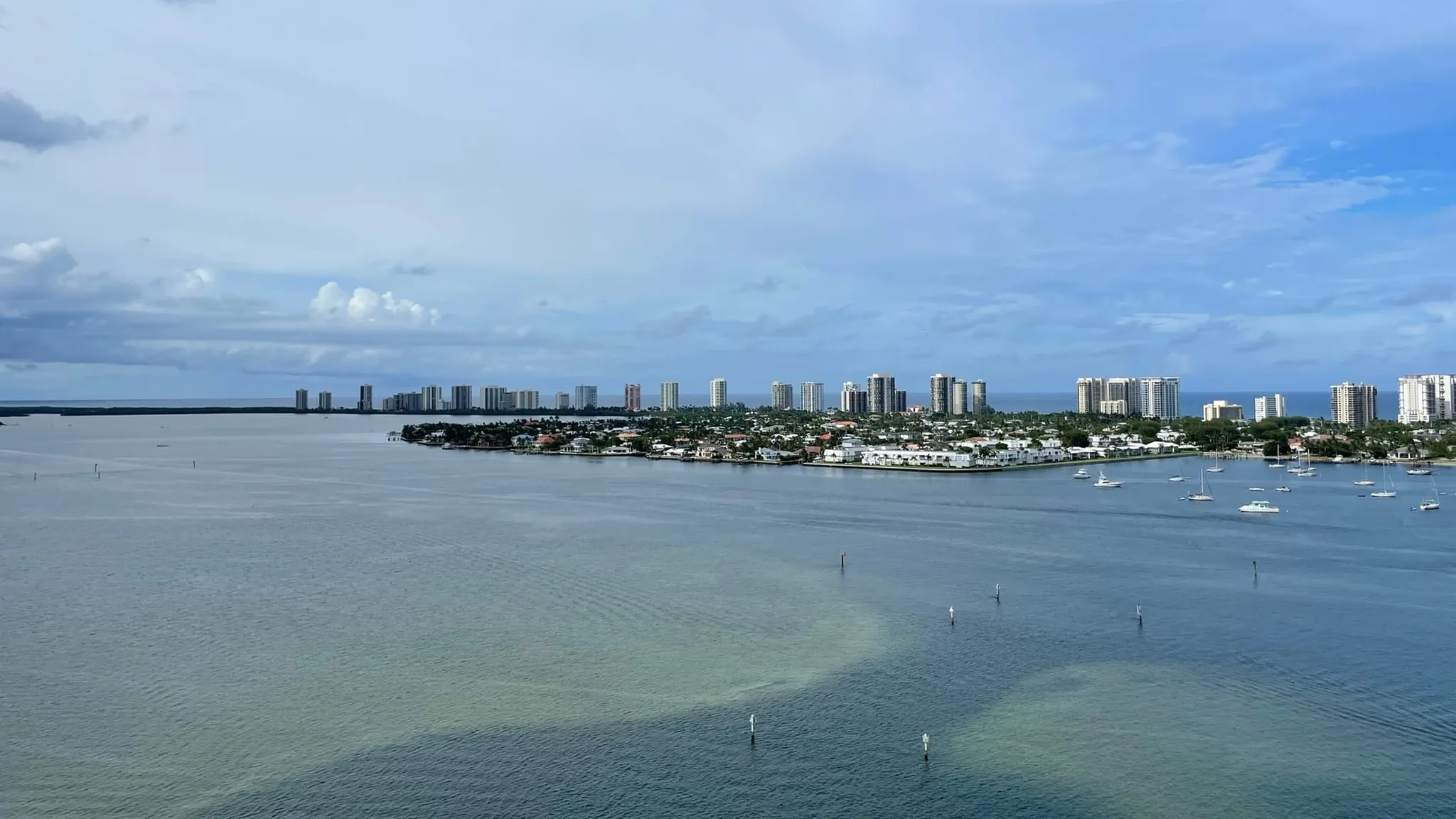 Singer Island's condominium skyline and lagoon-side homes seen across the Lake Worth Lagoon, with boats anchored off the shore