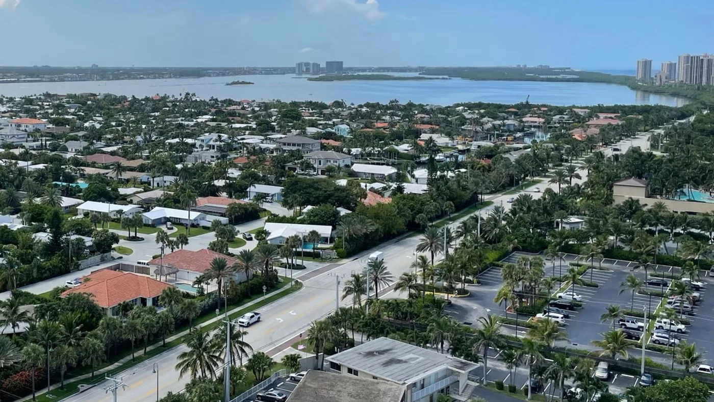 A high view over Singer Island's lagoon-side house streets to the lagoon, with Munyon Island, a long wooded island, in the distance