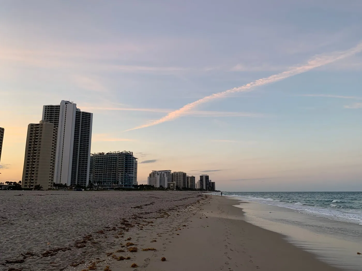A wide, empty Atlantic beach at dawn on Singer Island, with condominium towers set back from the sand