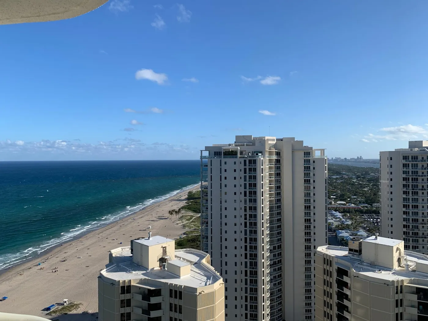 A high view along Singer Island's beach, with turquoise water, a wide strip of sand and condominium towers in the foreground