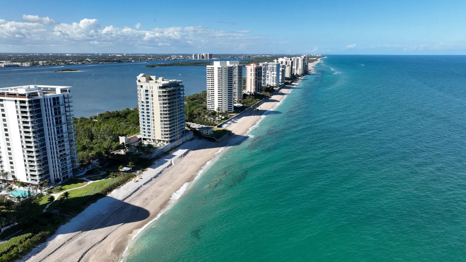Aerial view of oceanfront high-rise condominium towers along a barrier-island beach with turquoise Atlantic water