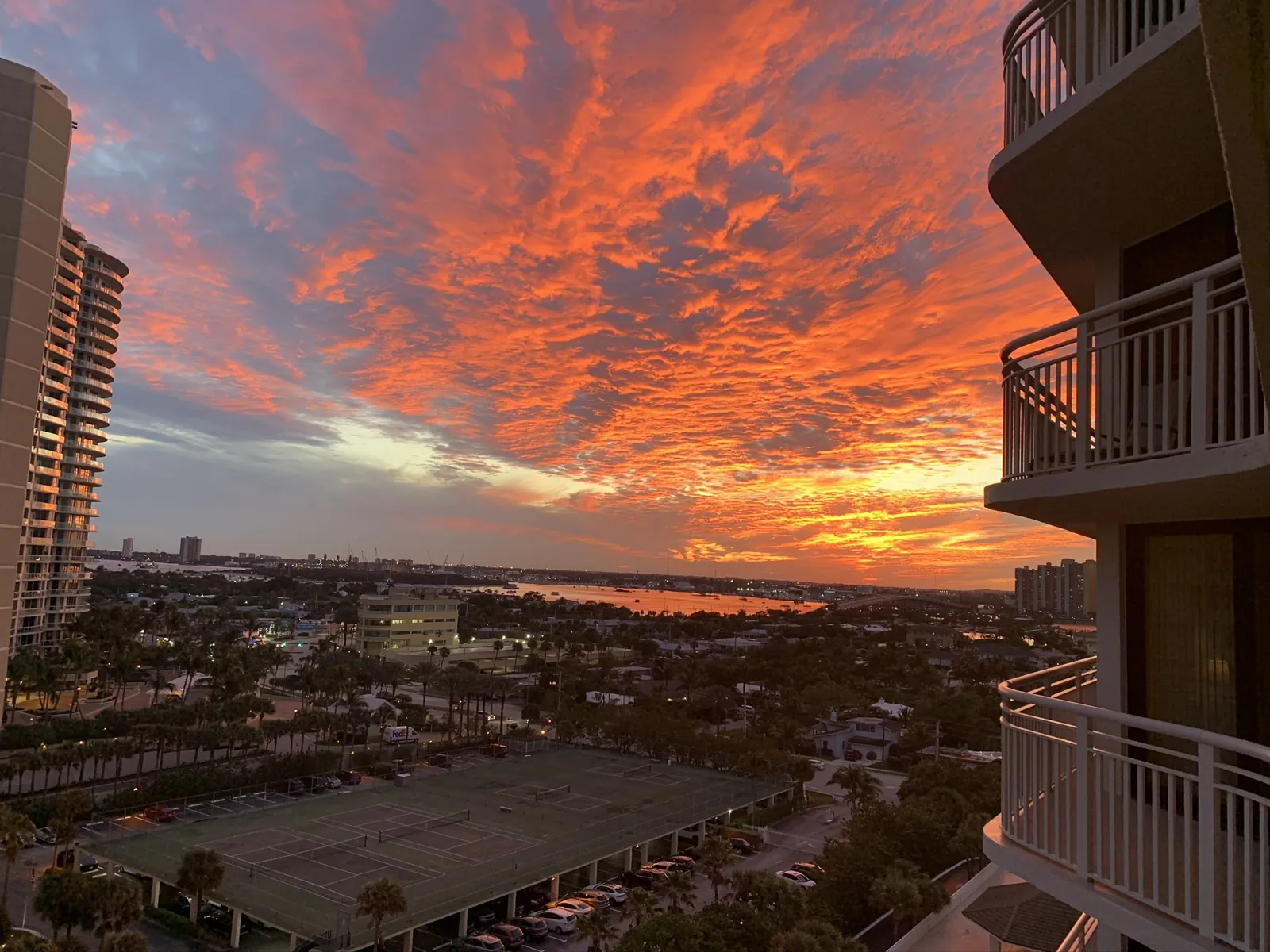 Vivid orange sunset over waterway seen from a high-rise balcony