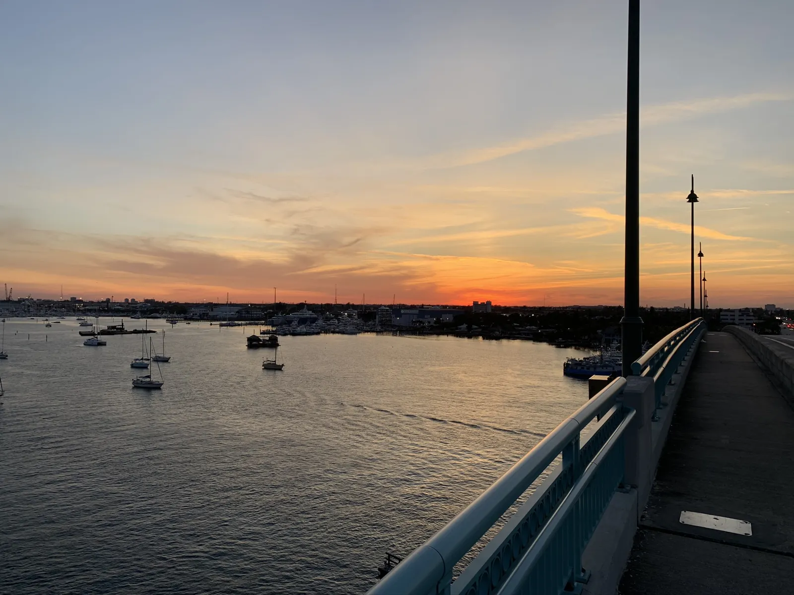 Sunset over a marina/waterway seen from a bridge walkway