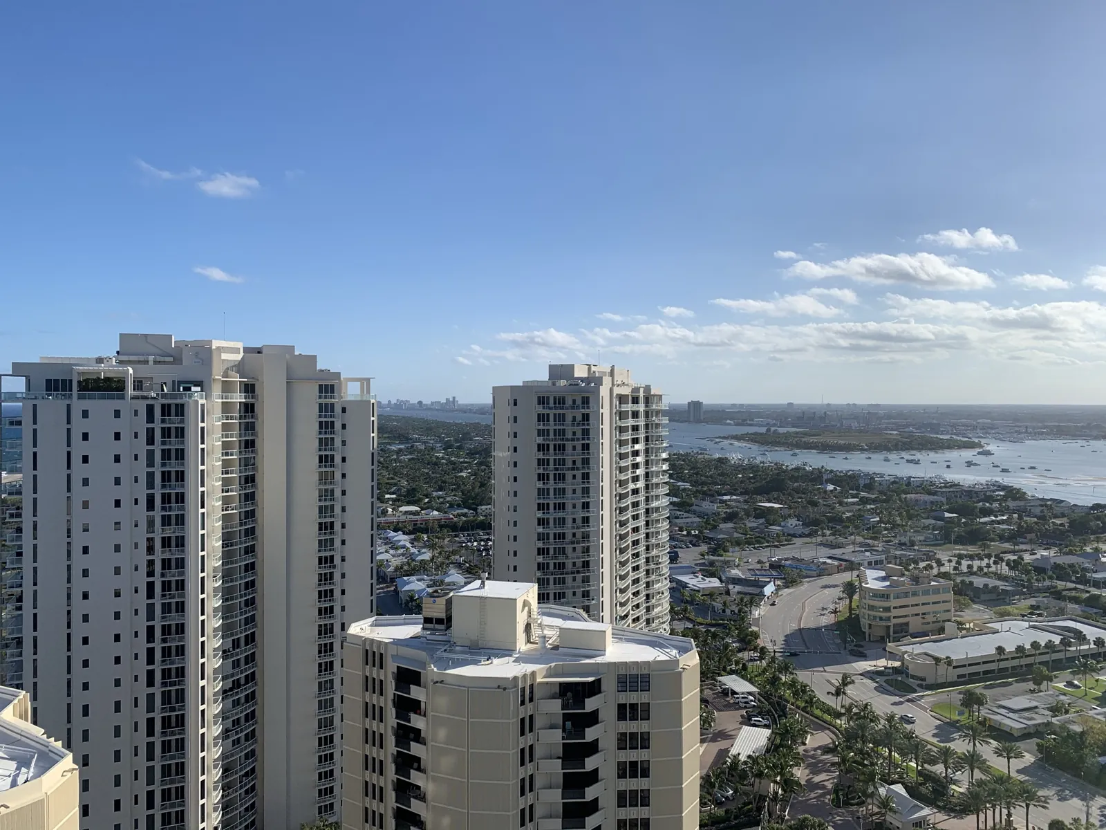 High-rise condo towers overlooking a waterway, inlet, and coastal neighborhood from an elevated balcony vantage