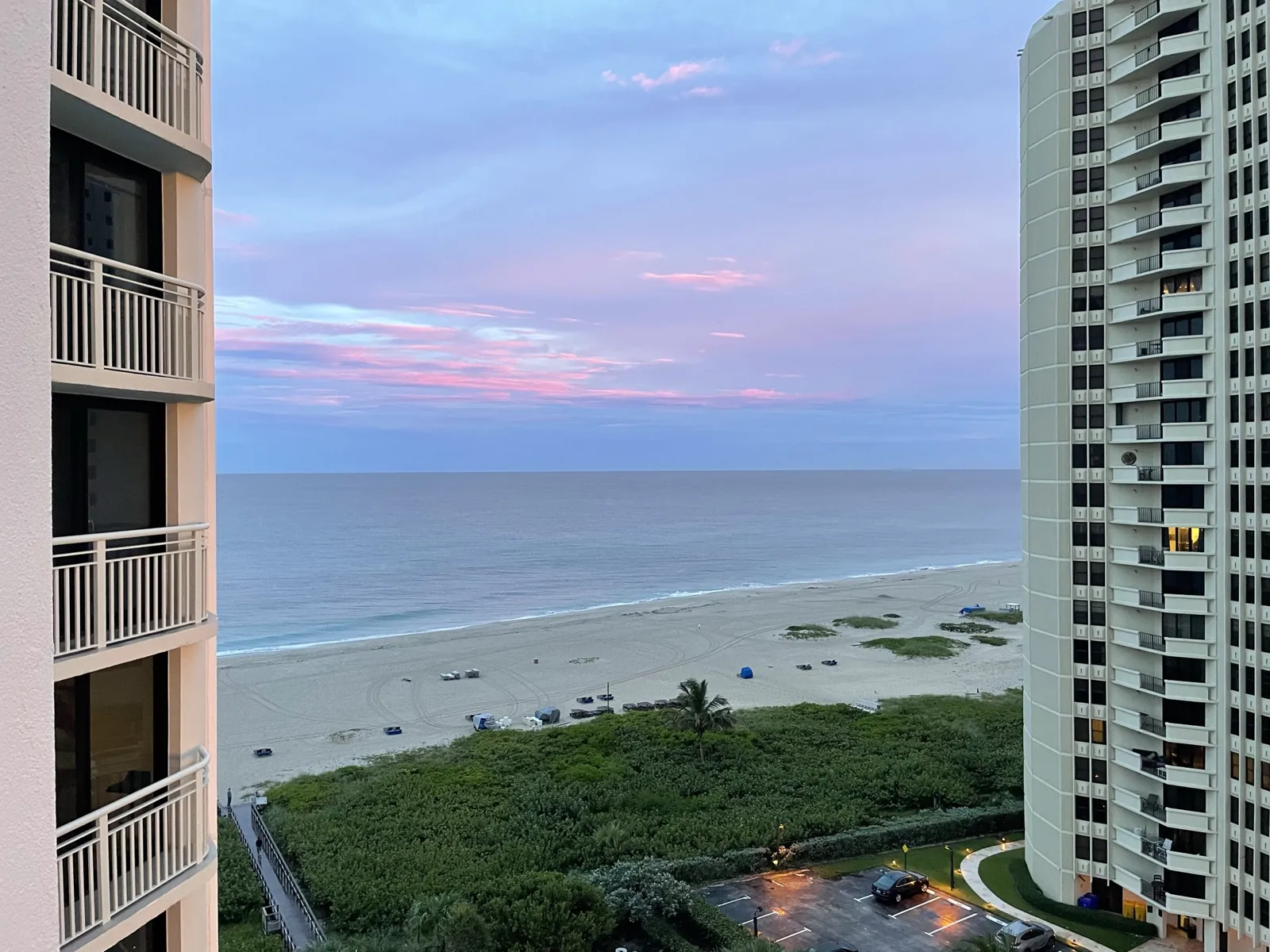Twilight ocean view between two high-rise condo towers with beach and dune vegetation