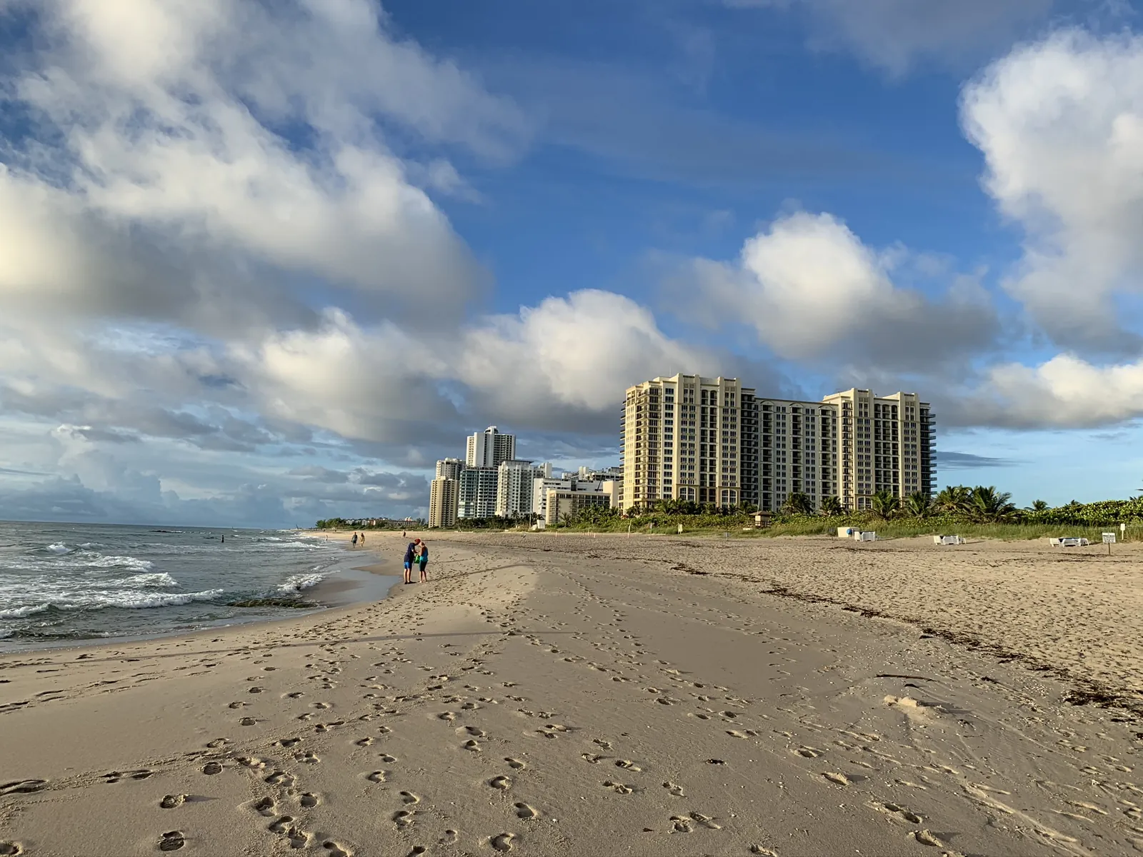 Wide sandy beach with oceanfront high-rise condominium towers under a dramatic cloudy sky