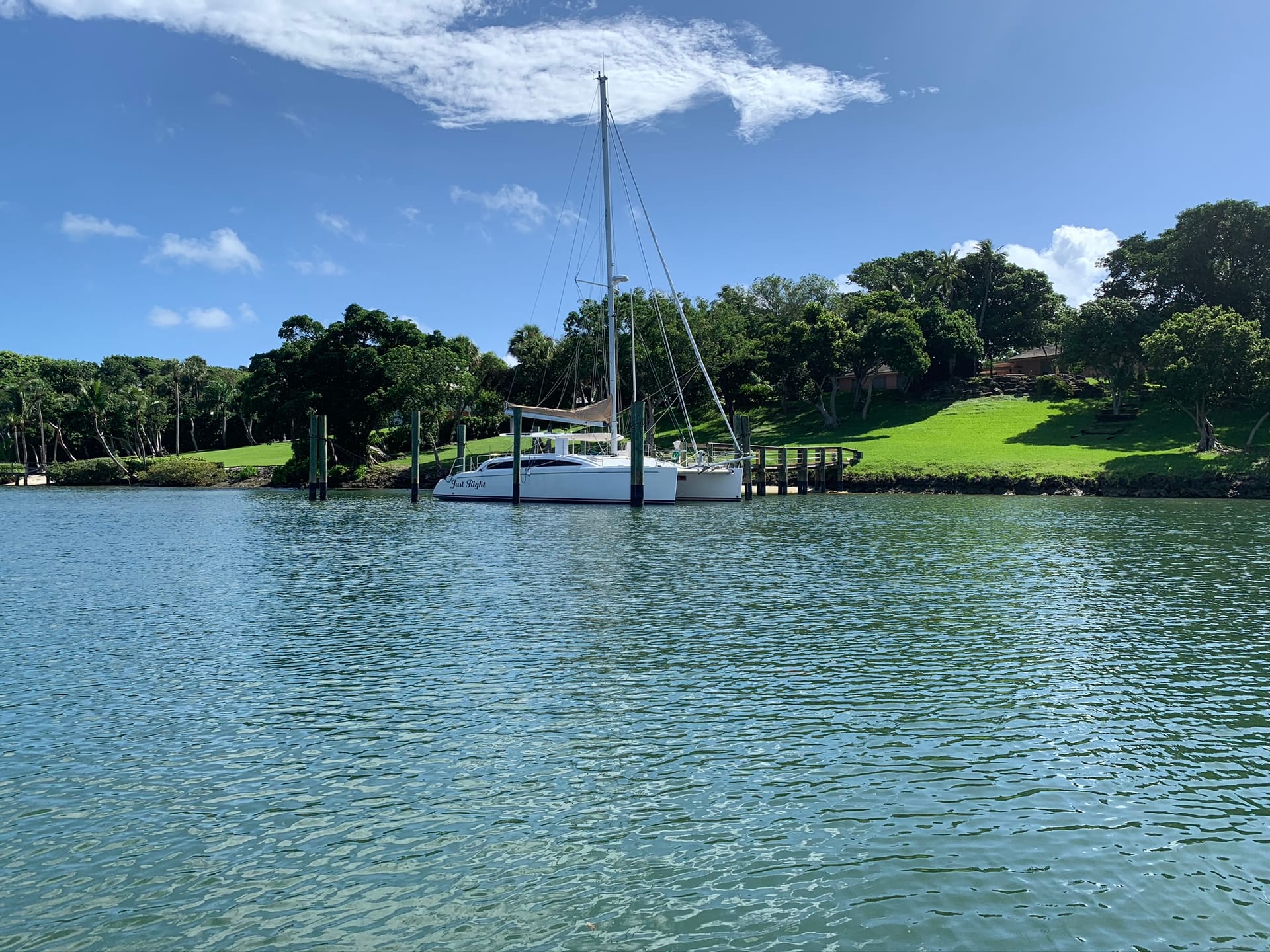A masted sailboat moored off a private dock on a sheltered waterway