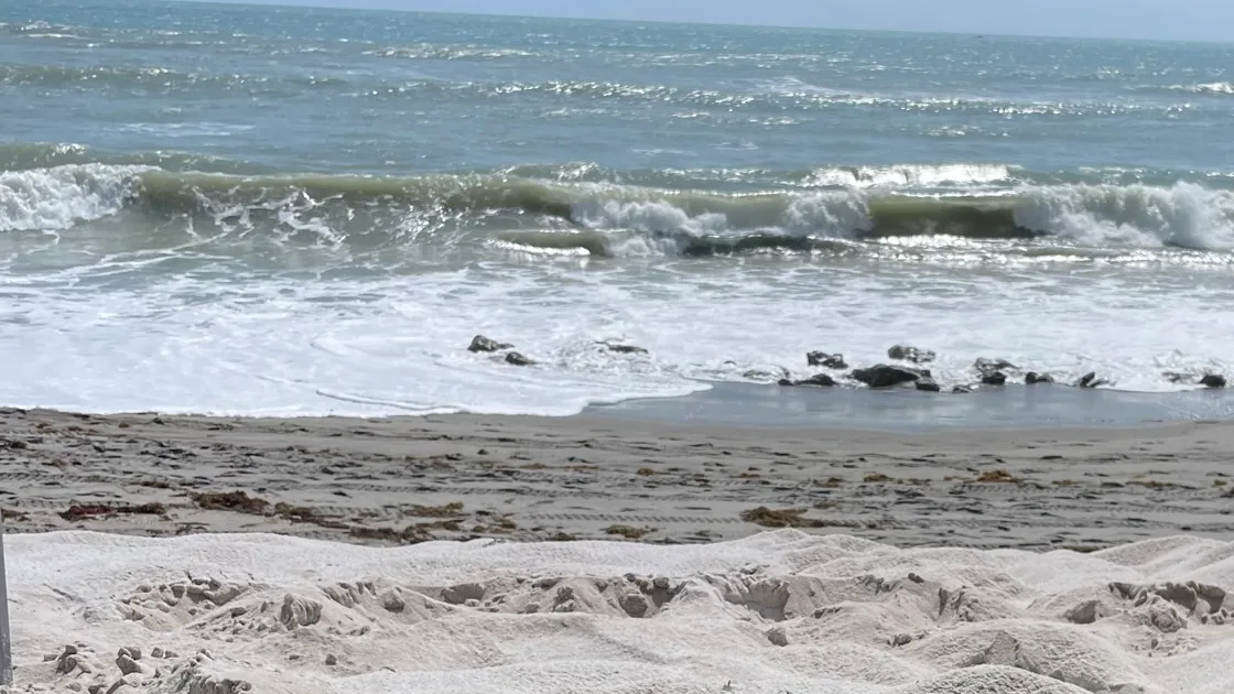 Surf breaking over rock outcrops along the sand at Coral Cove Park