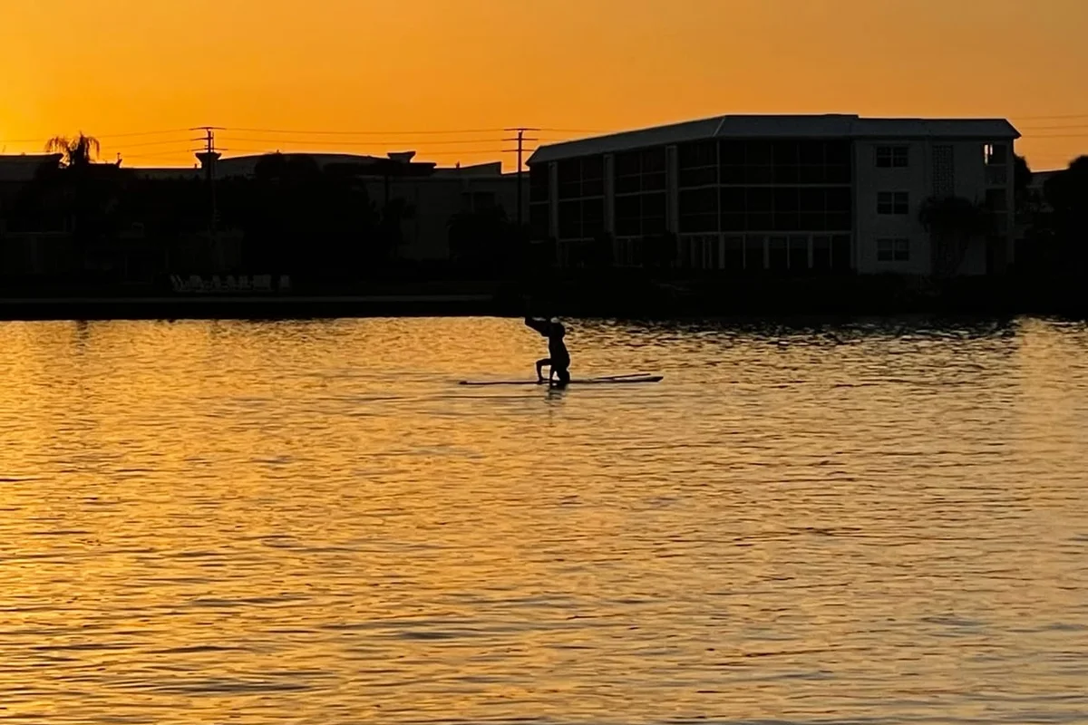 A paddleboarder silhouetted against a golden sunset on the Intracoastal in Tequesta