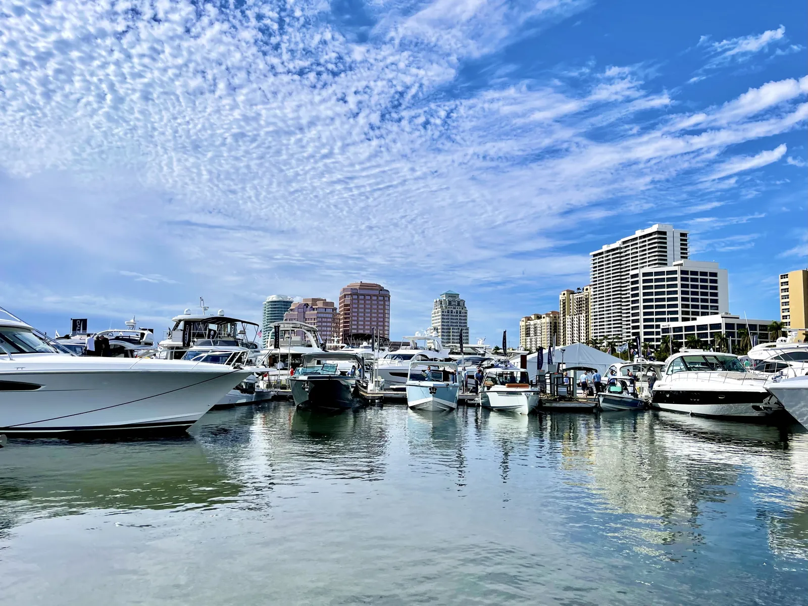 Boat show / marina with yachts against a downtown high-rise skyline under an altocumulus sky