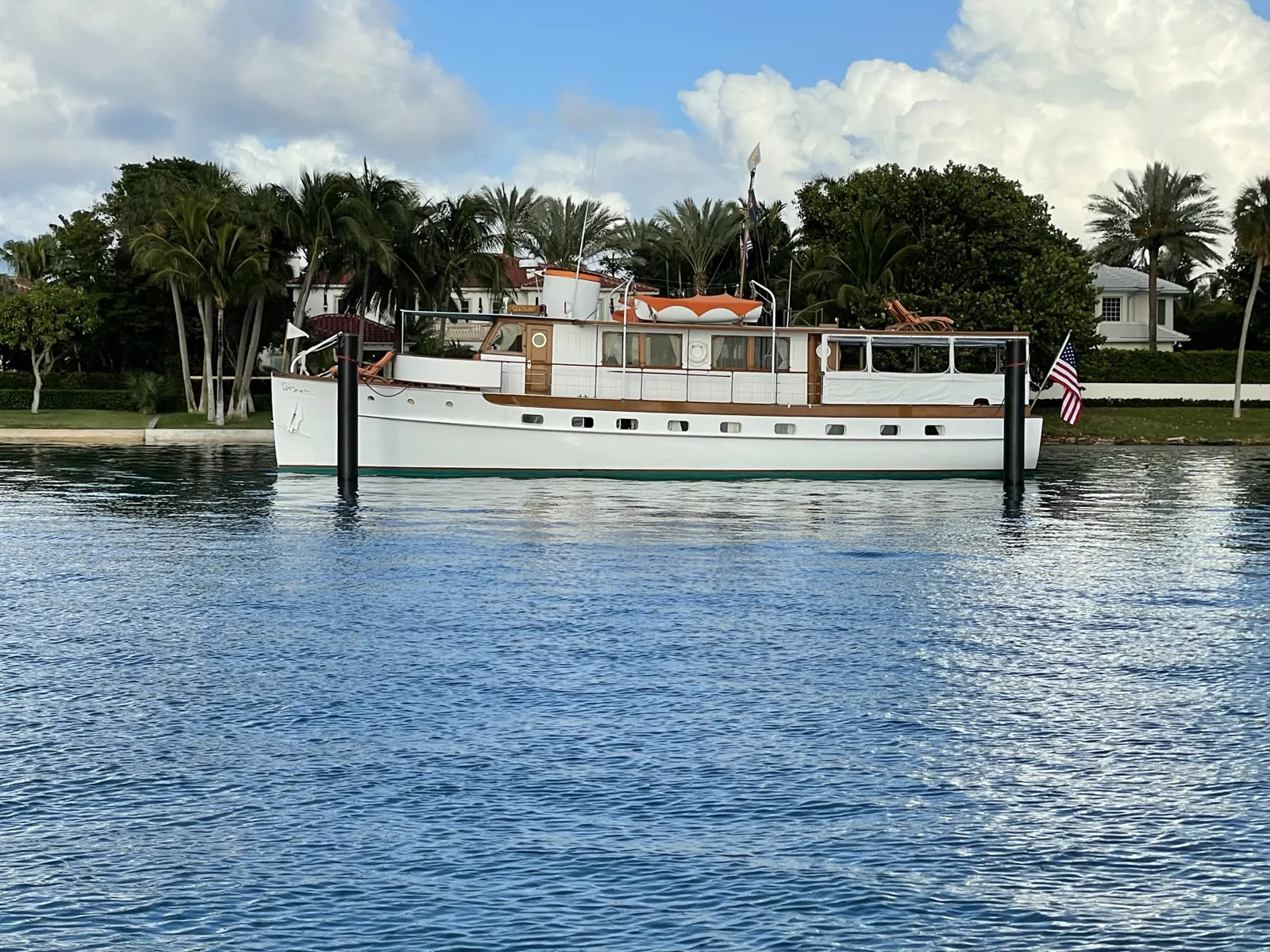 Classic white wooden motor yacht moored on the Intracoastal with waterfront estates behind