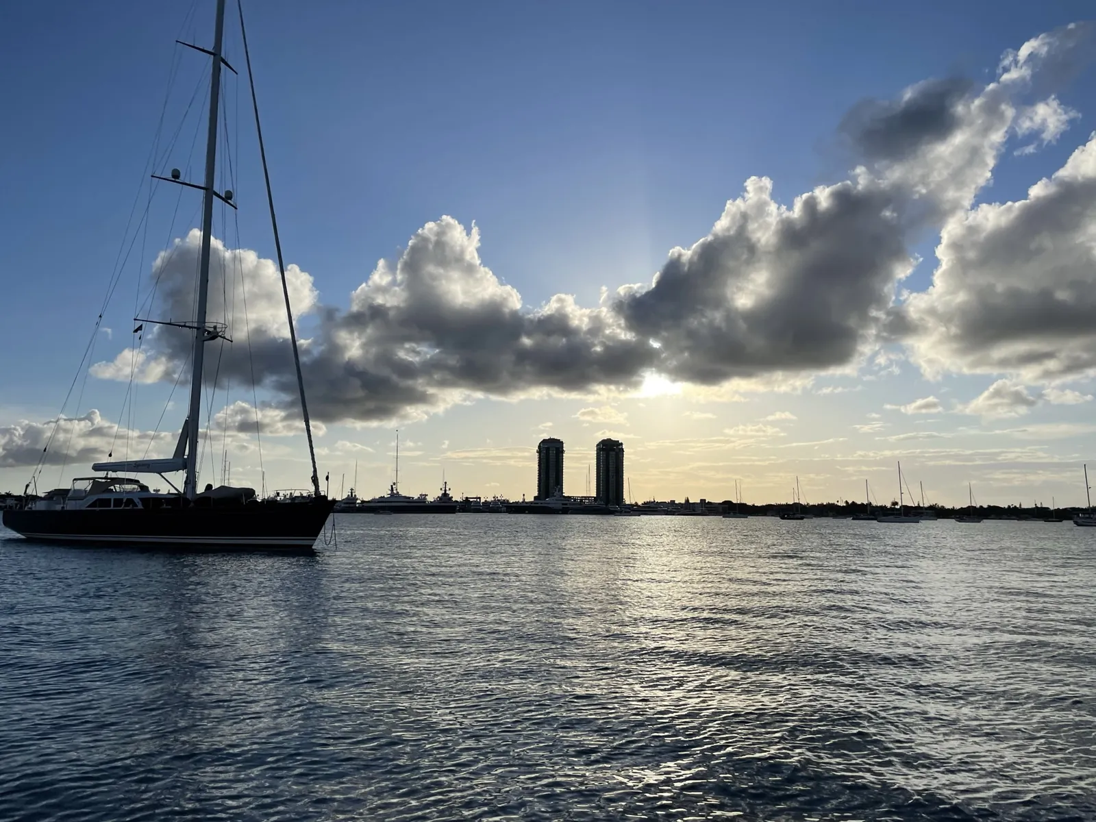 Sailing yacht at anchor on the Intracoastal at sunset with twin high-rise towers on the skyline