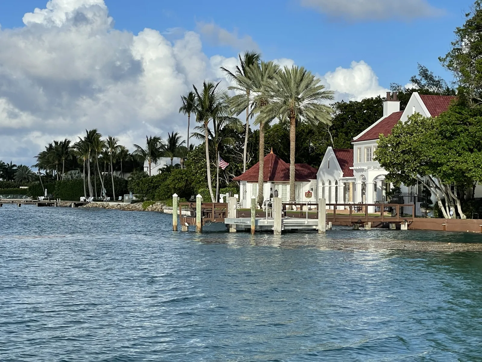 Waterfront estate with red-tile roofs, private dock and royal palms viewed from the water