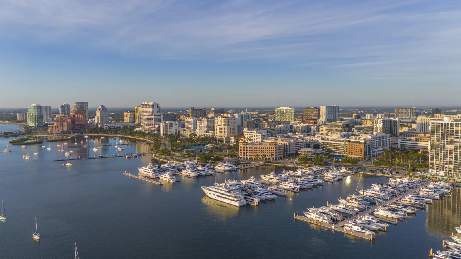 Aerial view of a downtown waterfront skyline and superyacht marina at golden hour
