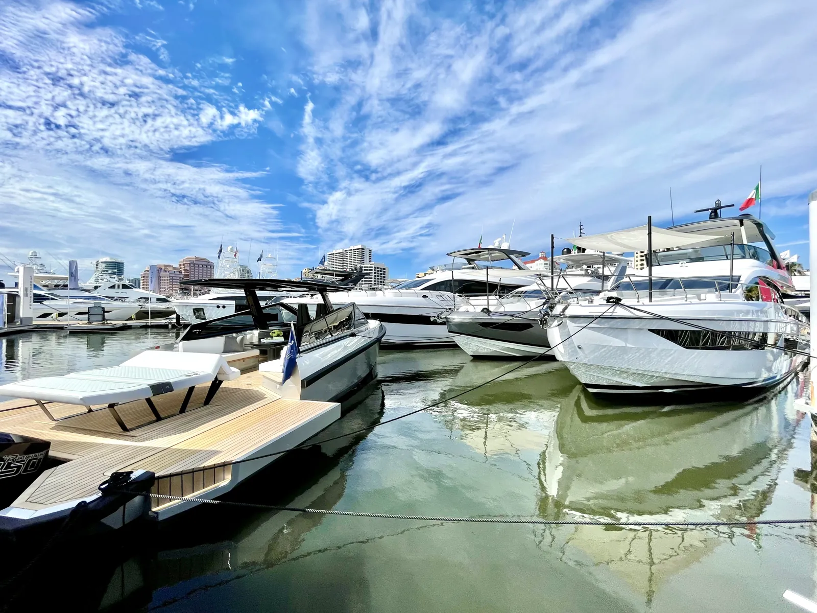 Luxury yachts moored at a downtown marina under a dramatic blue sky