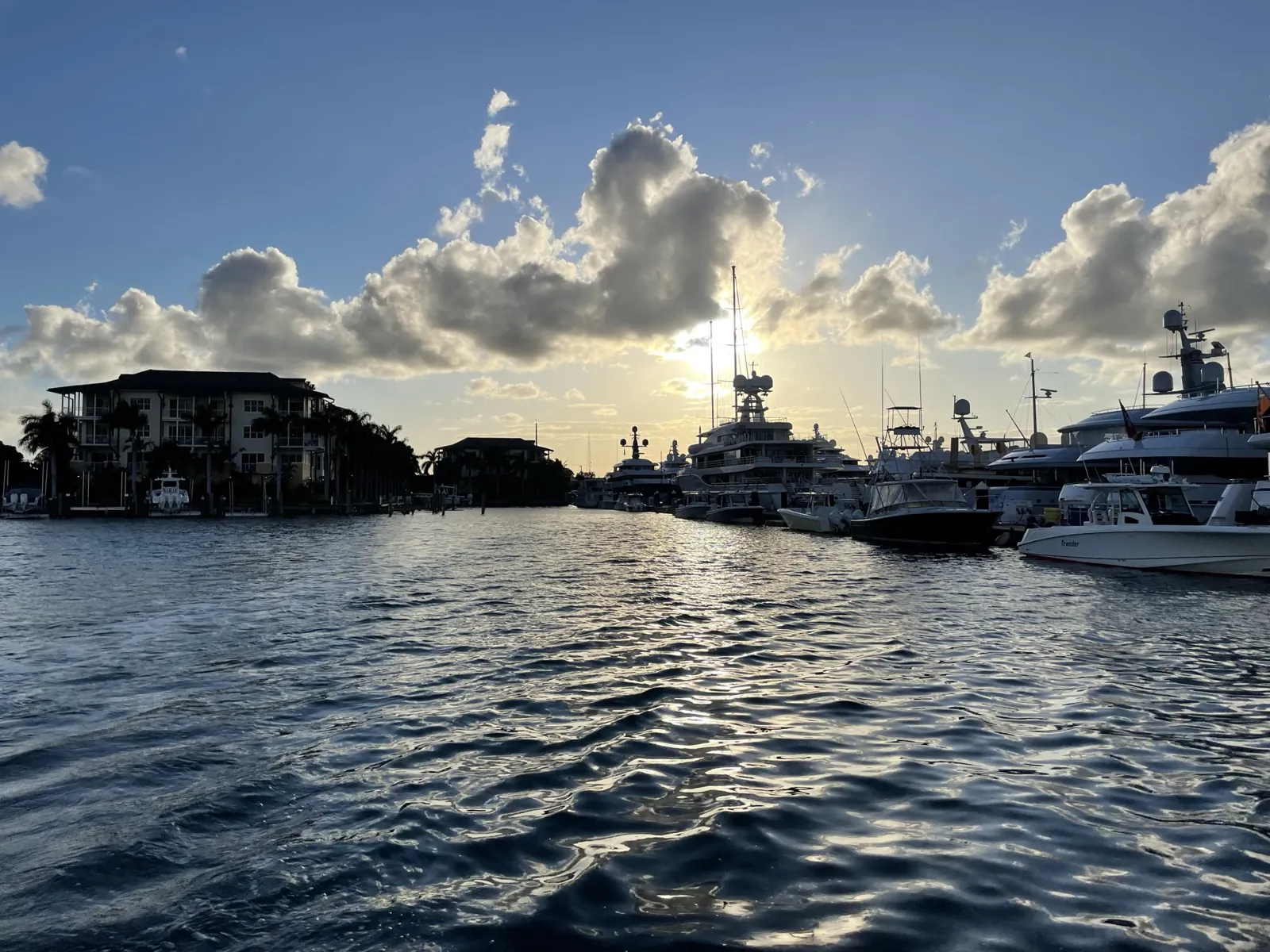 Sunset over a yacht-filled marina channel with waterfront residences