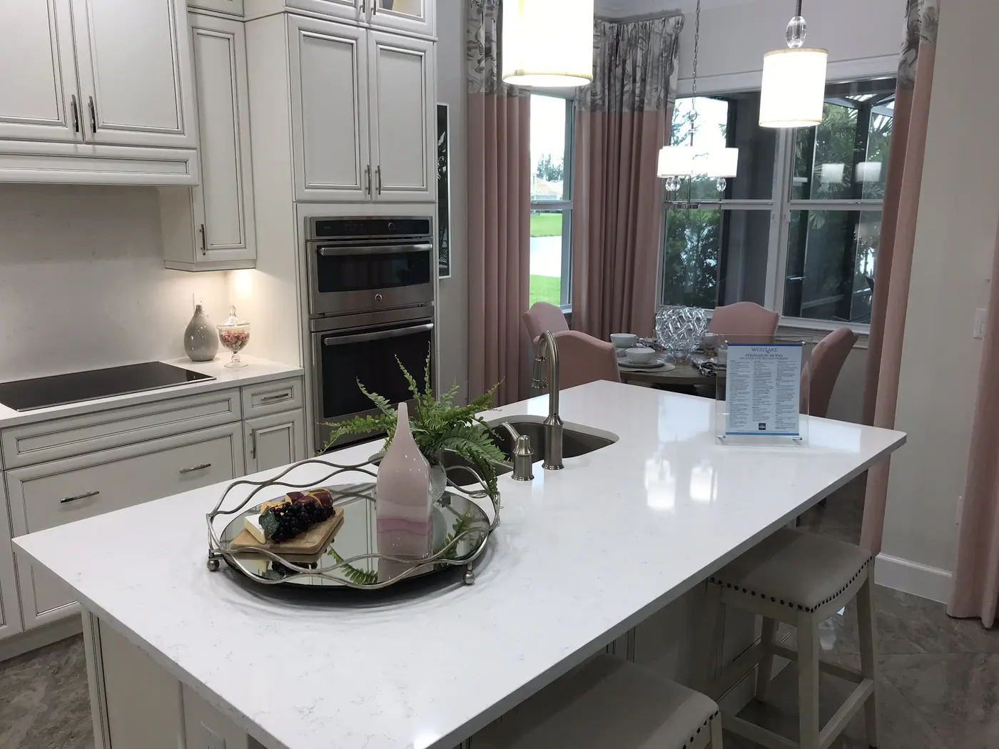 A white kitchen island with a decorative tray and a framed feature sheet in an acrylic stand, in a Minto model home in Westlake