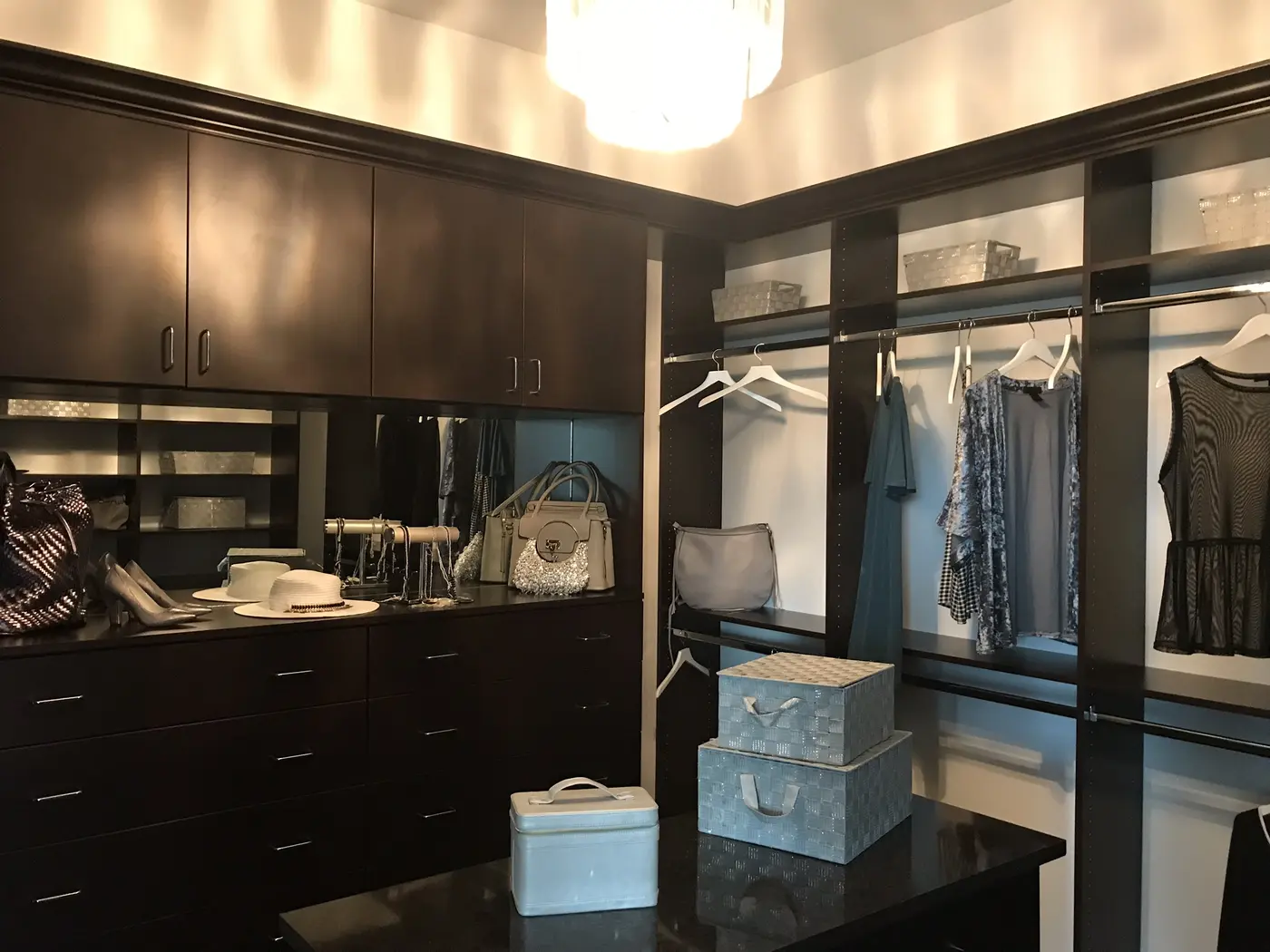 A walk-in closet with dark wood cabinetry, hanging rods and open shelving in a Minto model home in Westlake