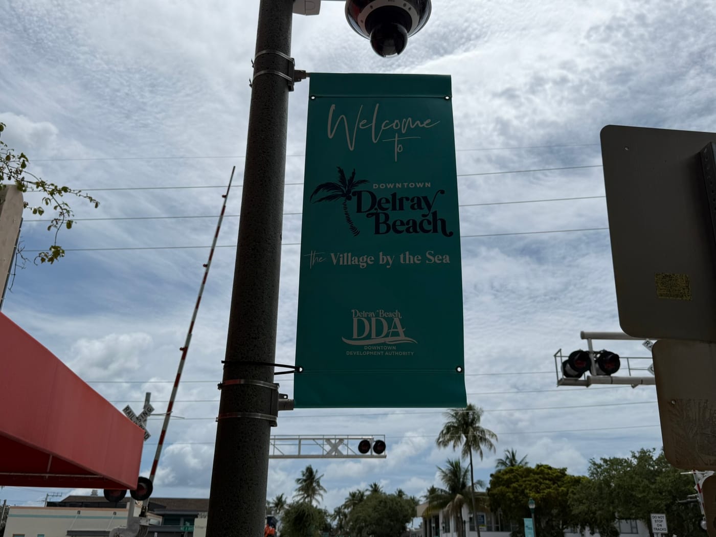 A Welcome to Downtown Delray Beach, The Village by the Sea banner on a downtown light pole