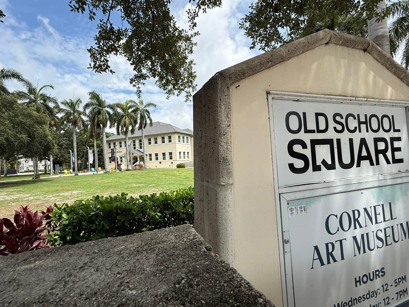 The Old School Square sign, listing the Cornell Art Museum, in front of a lawn and historic buildings